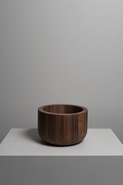 Brown walnut wood bowl sits on a grey studio background
