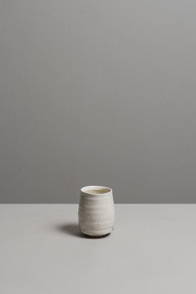 White ceramic cup on a gray surface with a gray background