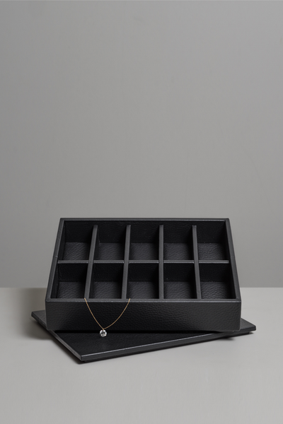 Black leather jewellery display storage box with a necklace with a medium sized diamond on a gray background