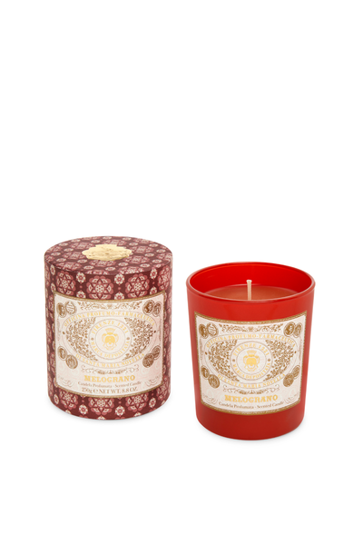 Red candle with decorative label next to its packaging on a white background