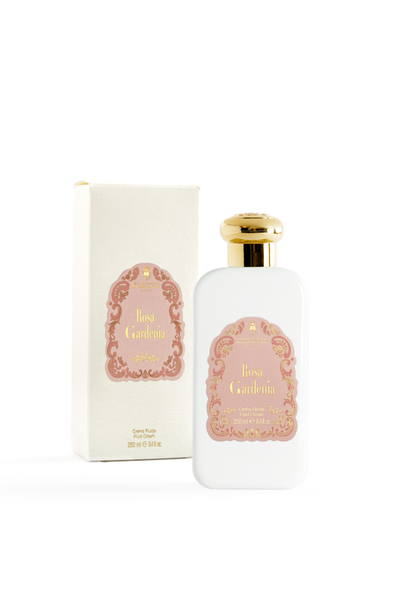 Bottle of rosa gardenia lotion on blank white background next to it's box, Box features a floral trim around the logo.