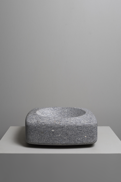 Gray stone bowl on a gray surface with a plain background